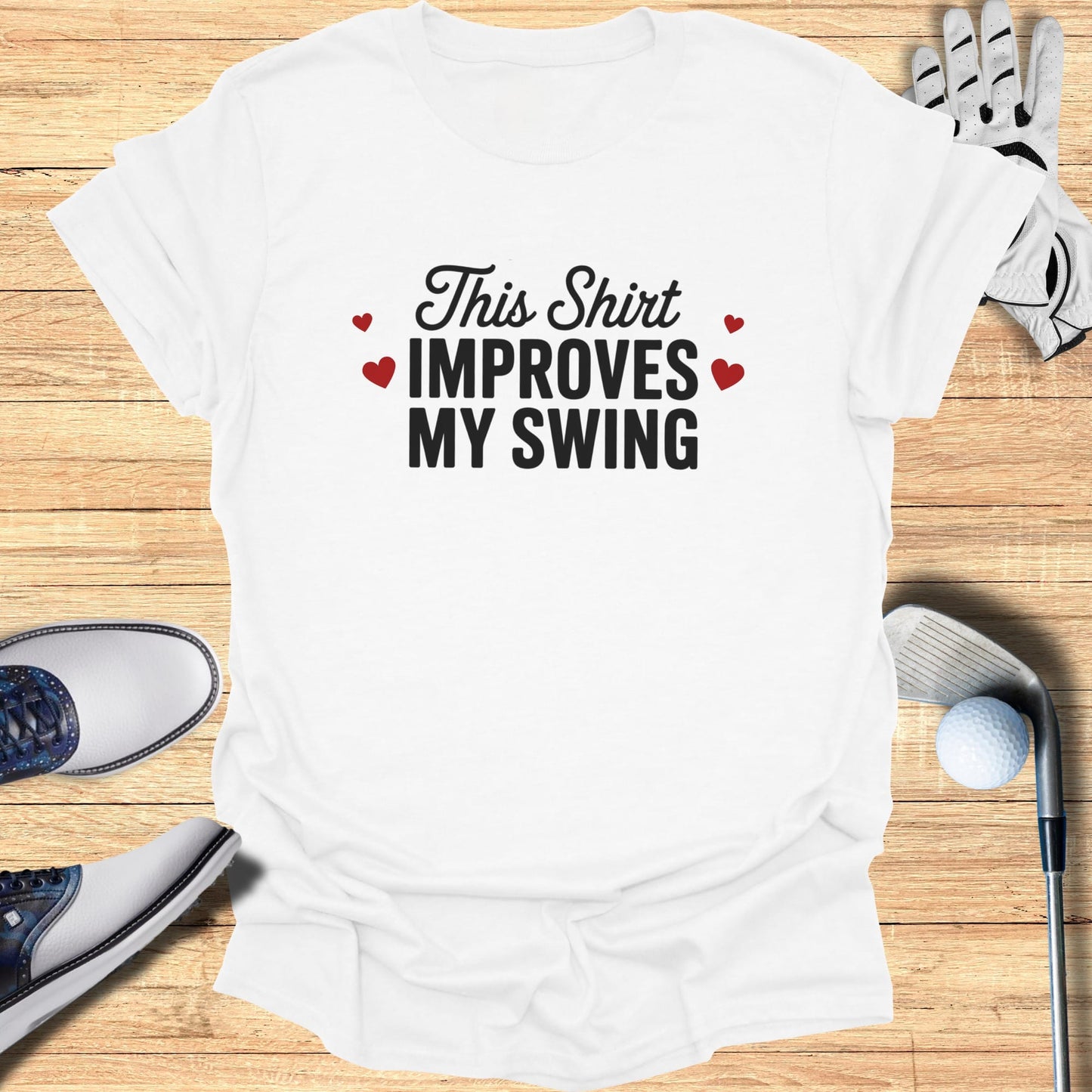 White t-shirt with "This Shirt Improves My Swing" text and golf accessories.