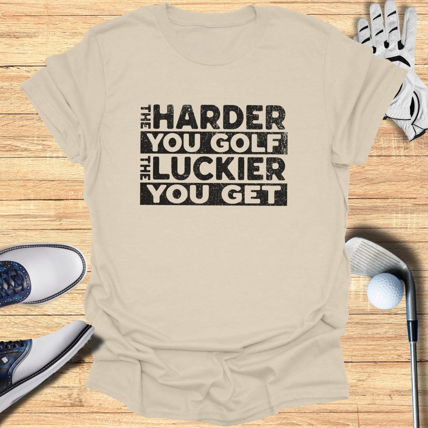 T-shirt with "The Harder You Golf, The Luckier You Get" text, golf clubs, shoes, and glove.