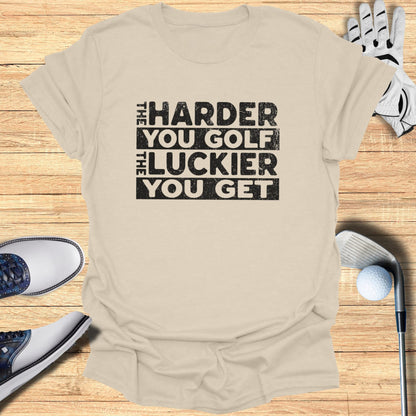 T-shirt with "The Harder You Golf, The Luckier You Get" text, golf clubs, shoes, and glove.