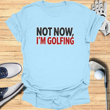 Light blue t-shirt with "NOT NOW, I'M GOLFING" text.