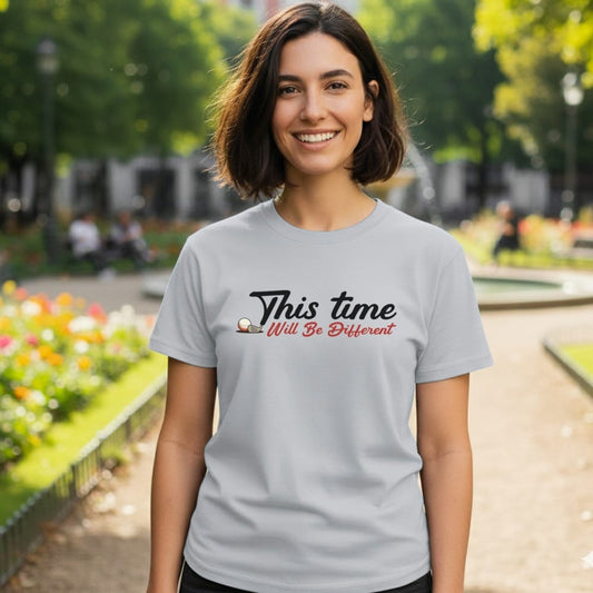 Light gray t-shirt with "This time will be different" text and golf ball.