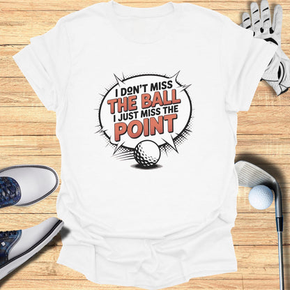 White t-shirt with "I don't miss the ball I just miss the point" text and golf ball graphic.