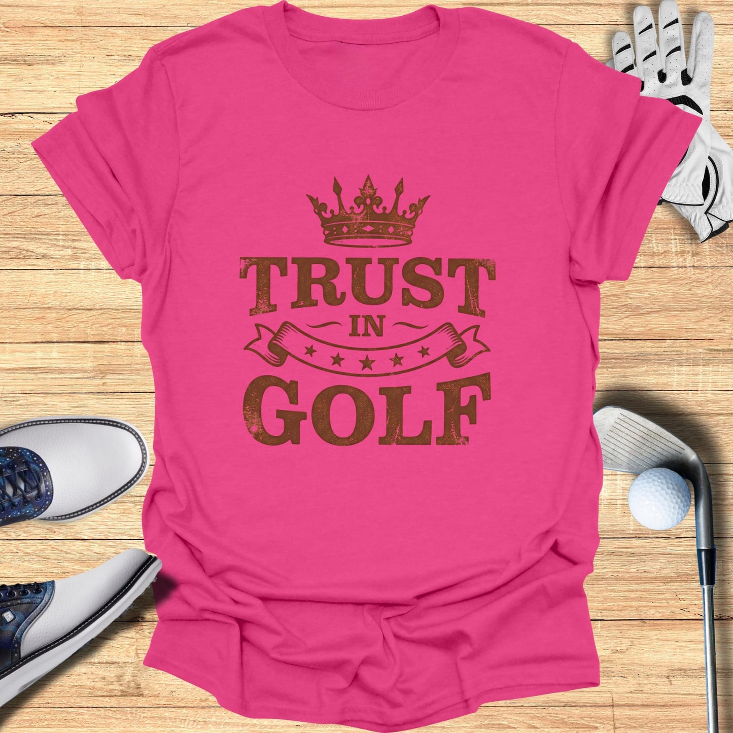Pink t-shirt with "TRUST IN GOLF" printed in a distressed brown font.
