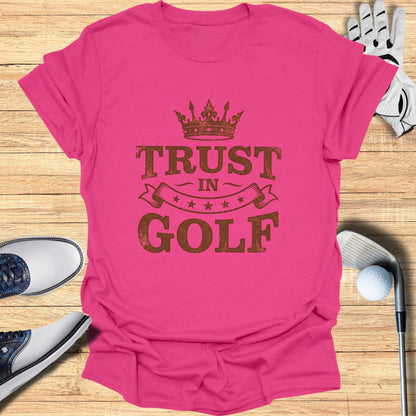 Pink t-shirt with "TRUST IN GOLF" printed in a distressed brown font.