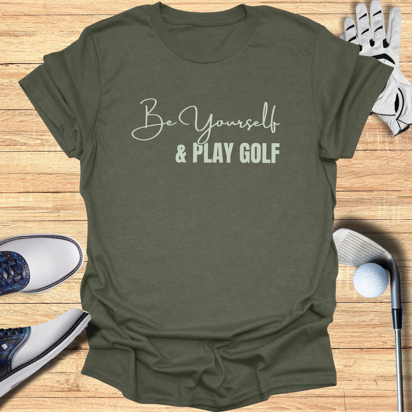Olive green t-shirt with "Be Yourself & Play Golf" text, golf shoes, glove, and ball.