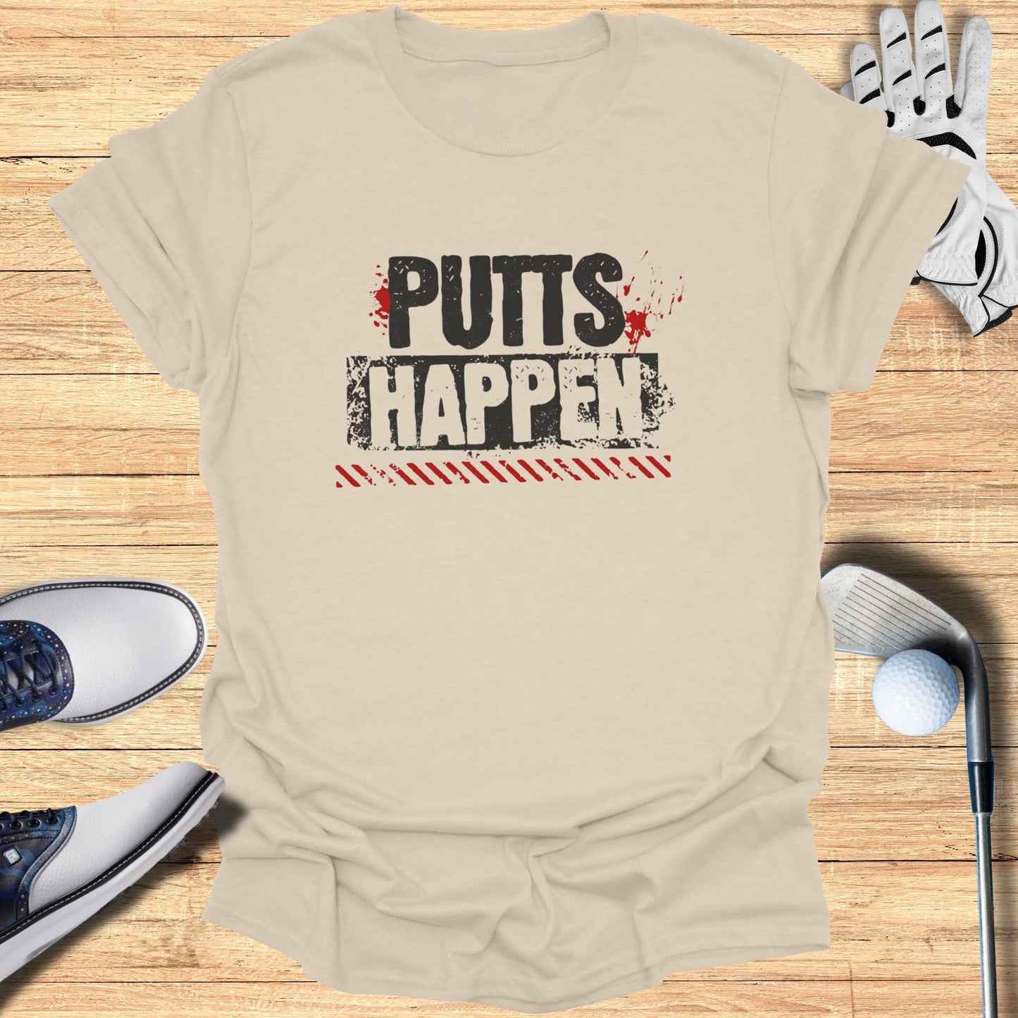 Cream t-shirt with "PUTTS HAPPEN" text, golf clubs, and balls.