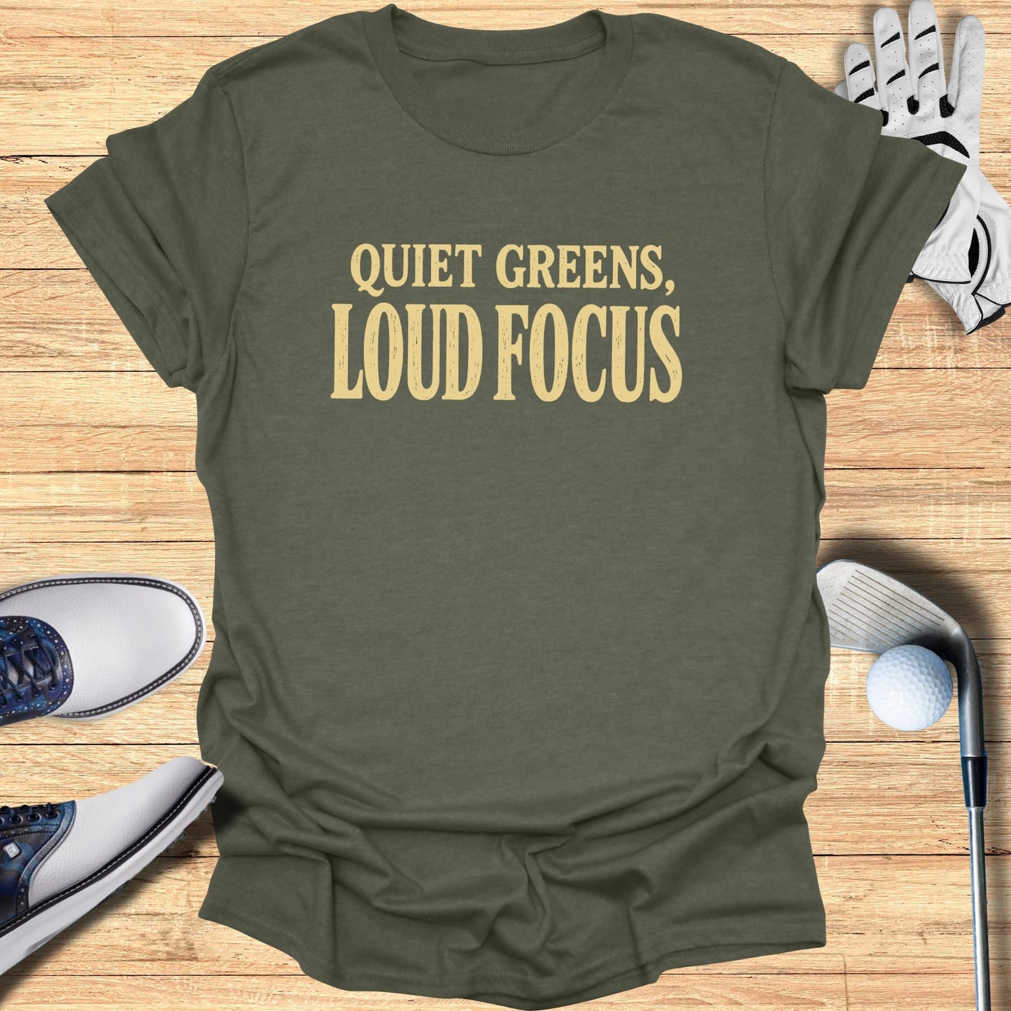 Olive green t-shirt with "QUIET GREENS, LOUD FOCUS" in gold text.