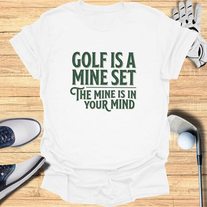White t-shirt with green text "GOLF IS A MINE SET THE MINE IS IN YOUR MIND".