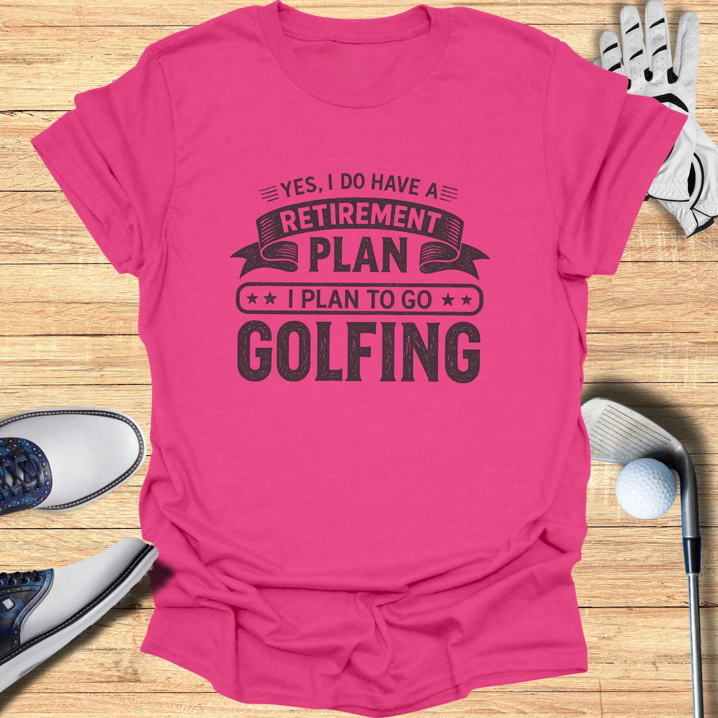 Pink t-shirt with "Retirement Plan: Golfing" text, surrounded by golf clubs and balls.