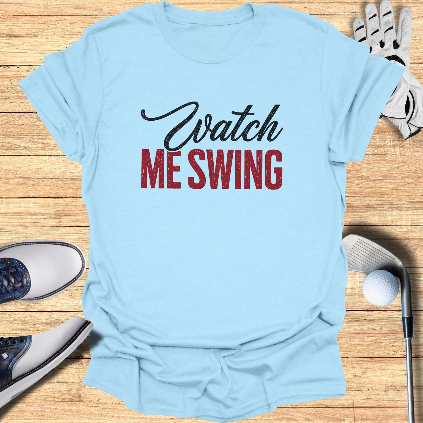 Light blue t-shirt with "Watch ME Swing" text, golf clubs, ball, and shoes.