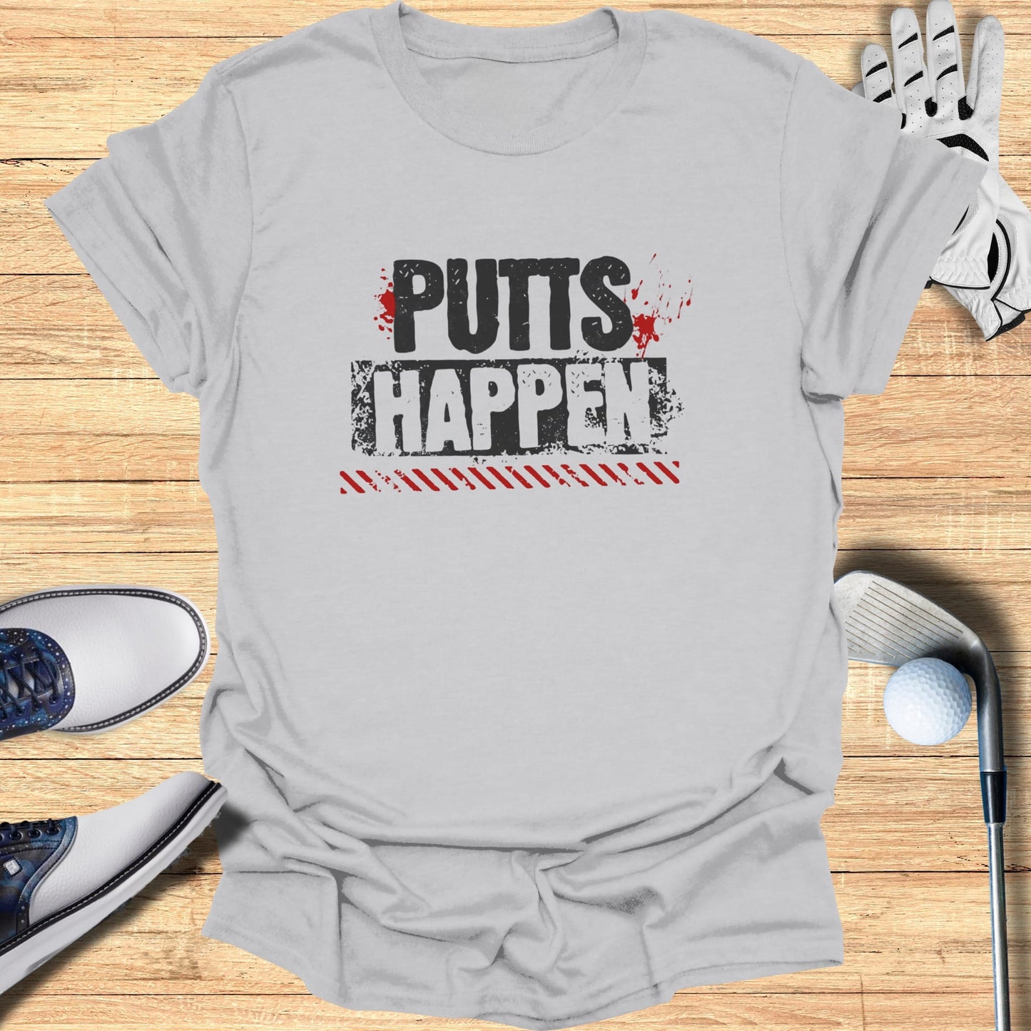 Gray t-shirt with "PUTTS HAPPEN" text, golf shoes, and club.