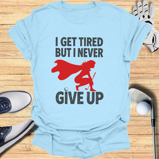 Light blue t-shirt with "I GET TIRED BUT I NEVER GIVE UP" and a superhero golfer graphic.