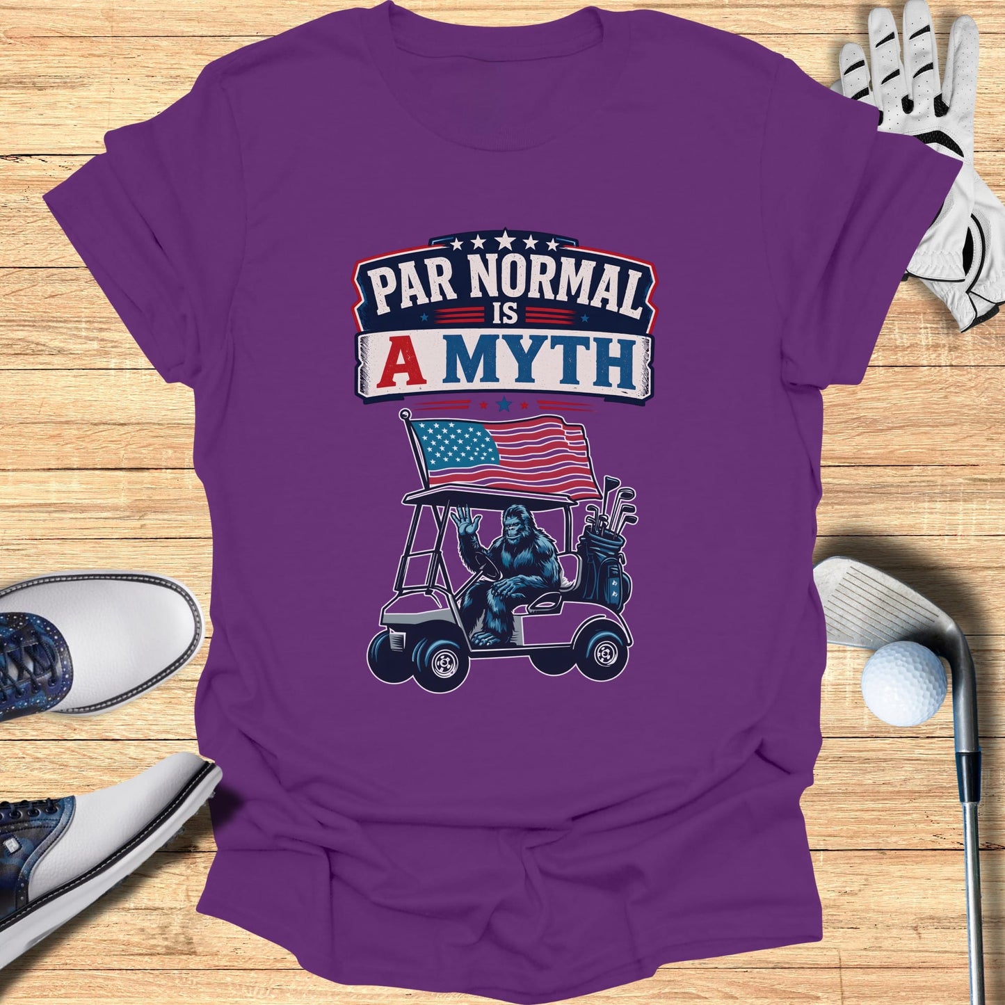 T-shirt with Bigfoot driving a golf cart, American flag, "Par Normal is a Myth" text.