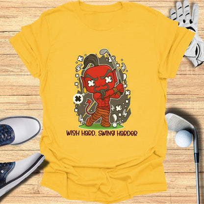 Yellow t-shirt with cartoon devil playing golf, "Wish Hard. Swing Harder."