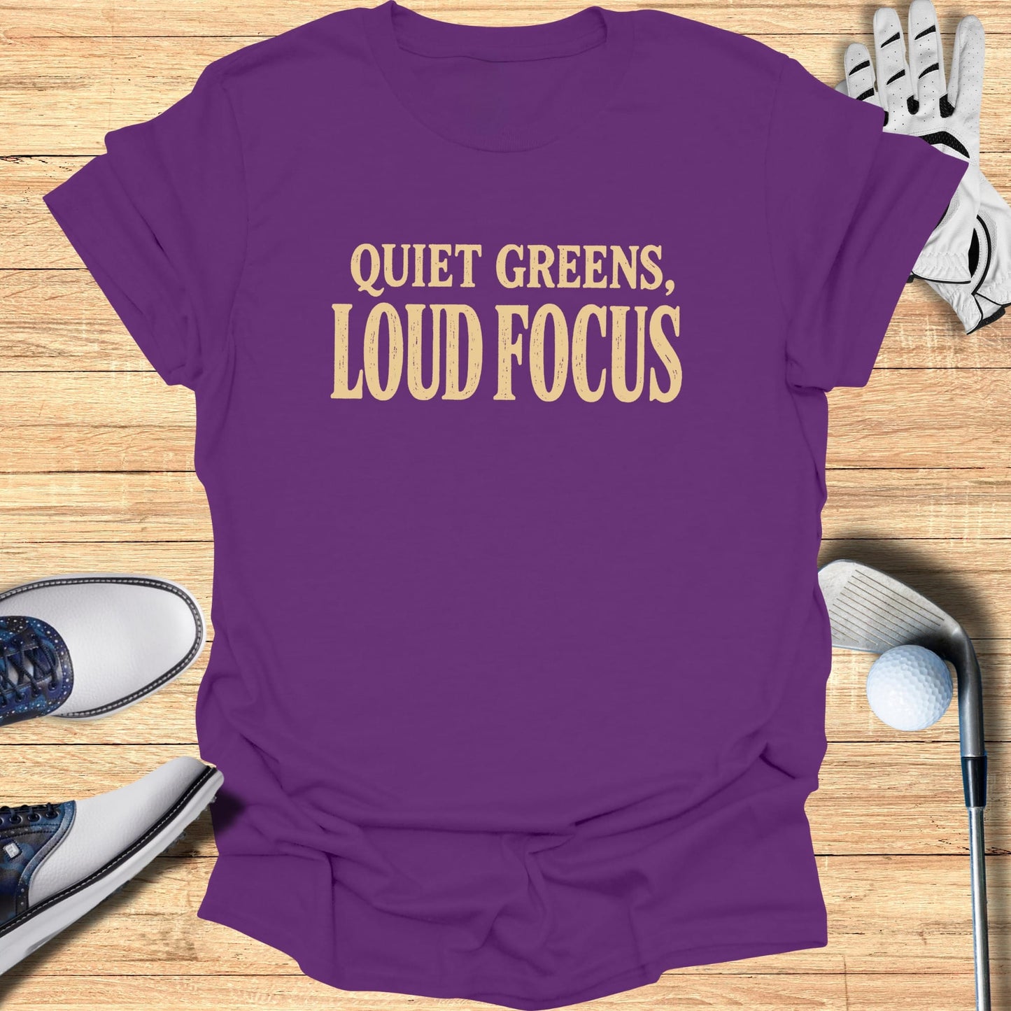 Purple t-shirt with "Quiet Greens, Loud Focus" text, golf shoes, glove, and ball.