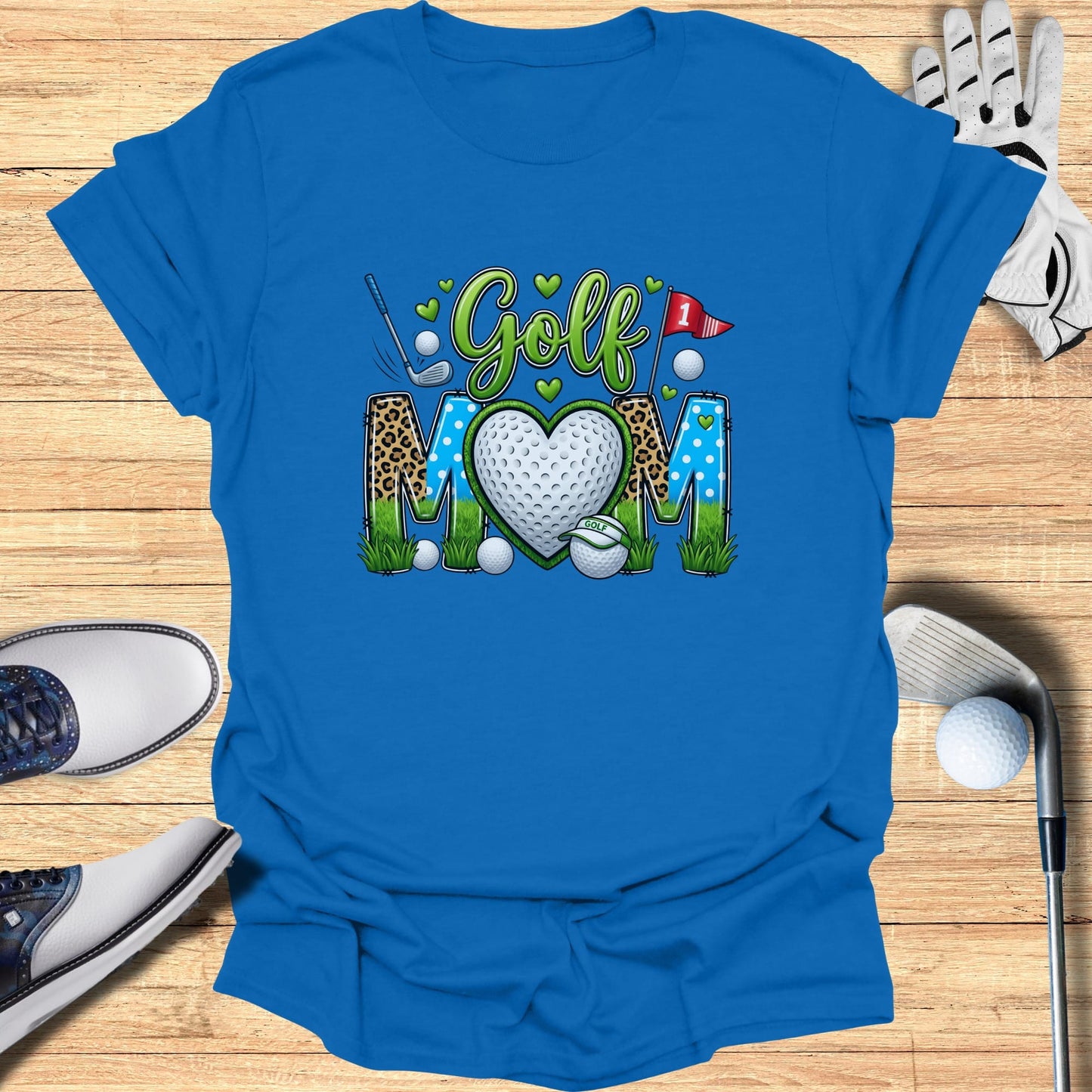 Blue t-shirt with "Golf Mom" text and heart graphic, golf accessories surround.