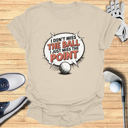 Light beige t-shirt with "I don't miss the ball, I just miss the point" graphic.
