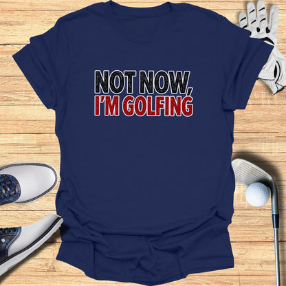 Navy t-shirt with "NOT NOW, I'M GOLFING" text, with golf shoes and ball.