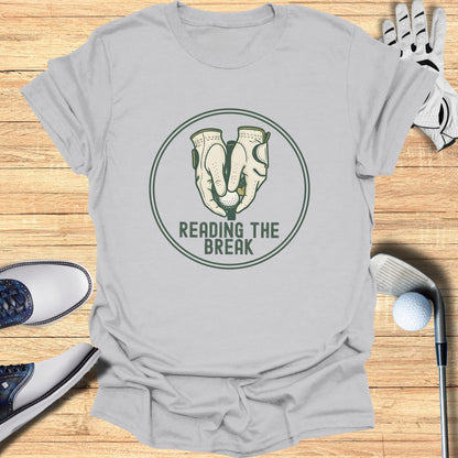 Golf gloves holding a ball above "READING THE BREAK" text.