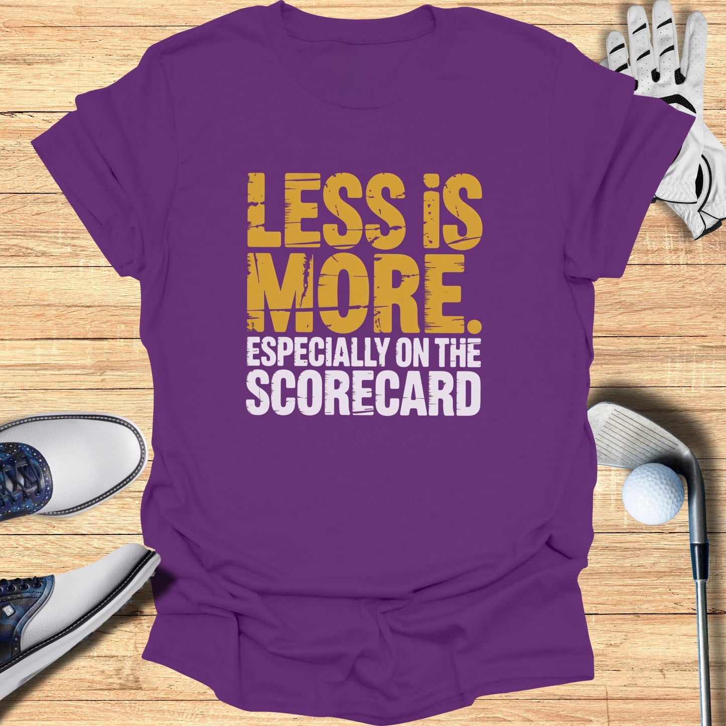 Purple t-shirt with "LESS IS MORE. ESPECIALLY ON THE SCORECARD." text.