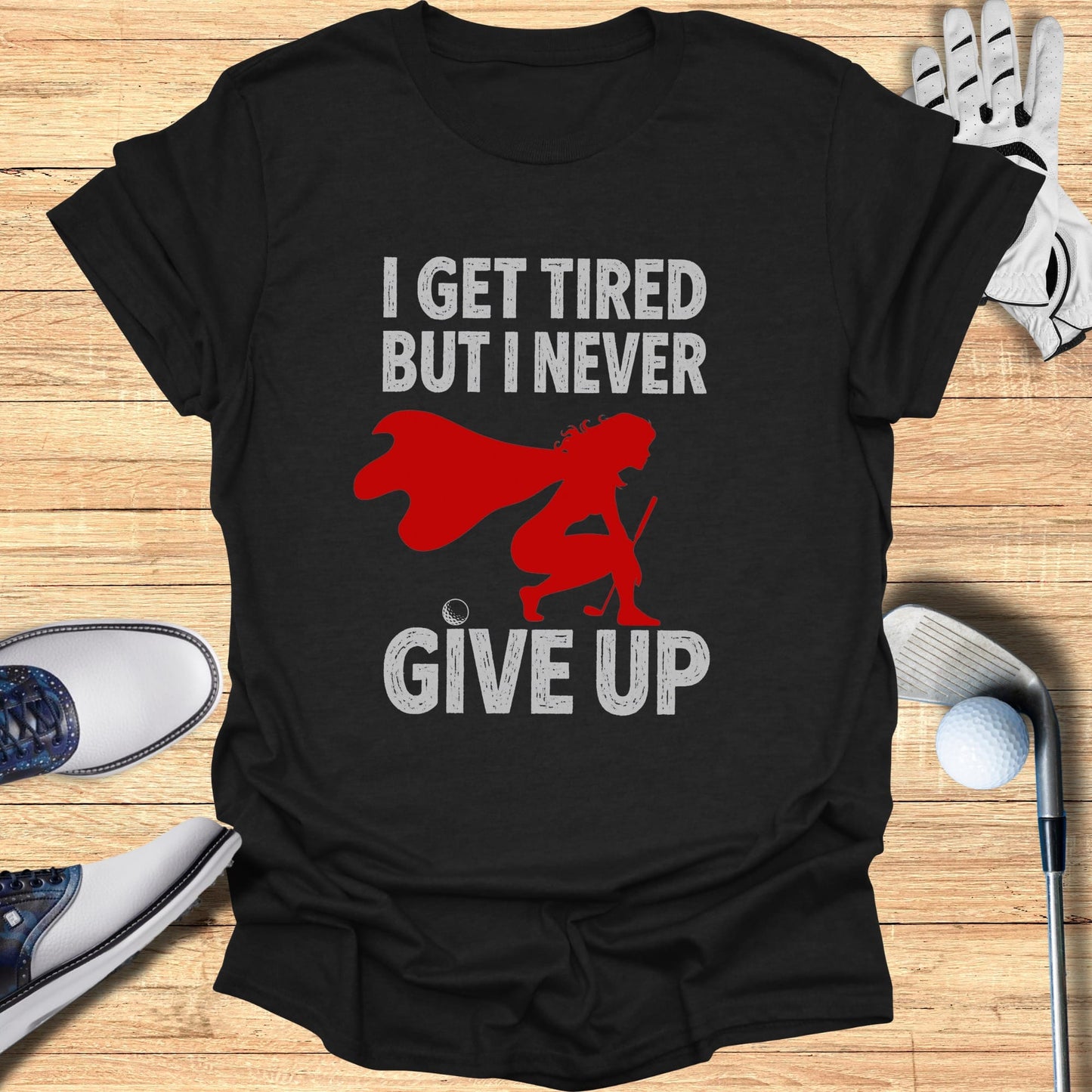 Black t-shirt with "I GET TIRED BUT I NEVER GIVE UP" and a superhero golfer.
