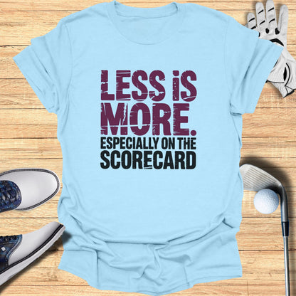 Light blue t-shirt with "LESS IS MORE. ESPECIALLY ON THE SCORECARD." text.