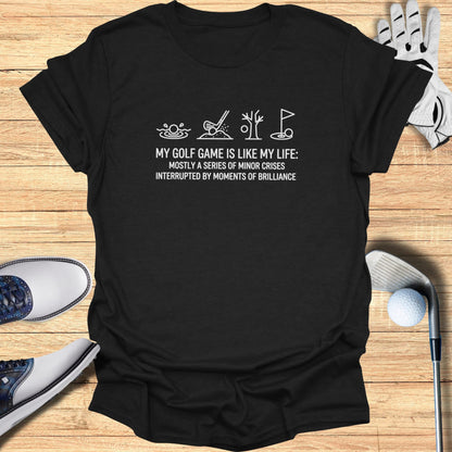 Black t-shirt with white text: "MY GOLF GAME IS LIKE MY LIFE: MOSTLY A SERIES OF MINOR CRISES INTERRUPTED BY MOMENTS OF BRILLIANCE"