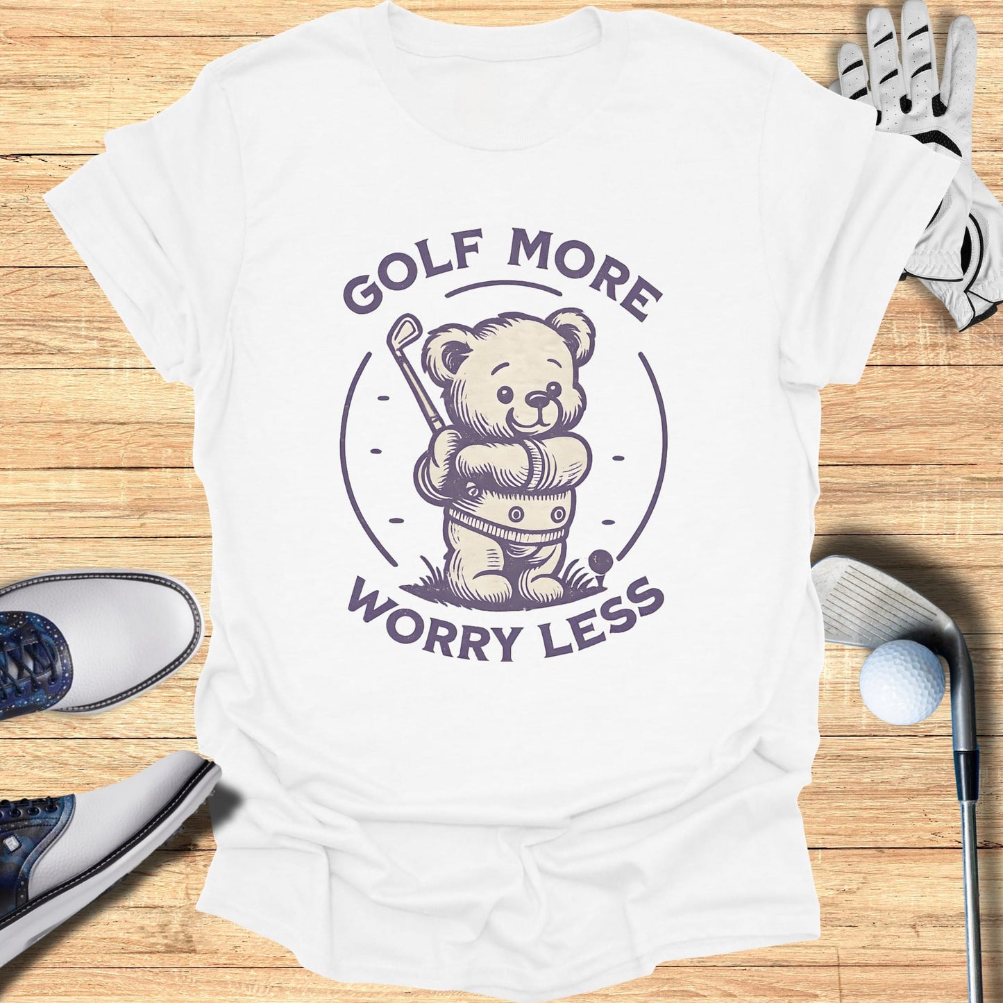 White t-shirt with purple text and graphics of a teddy bear playing golf.