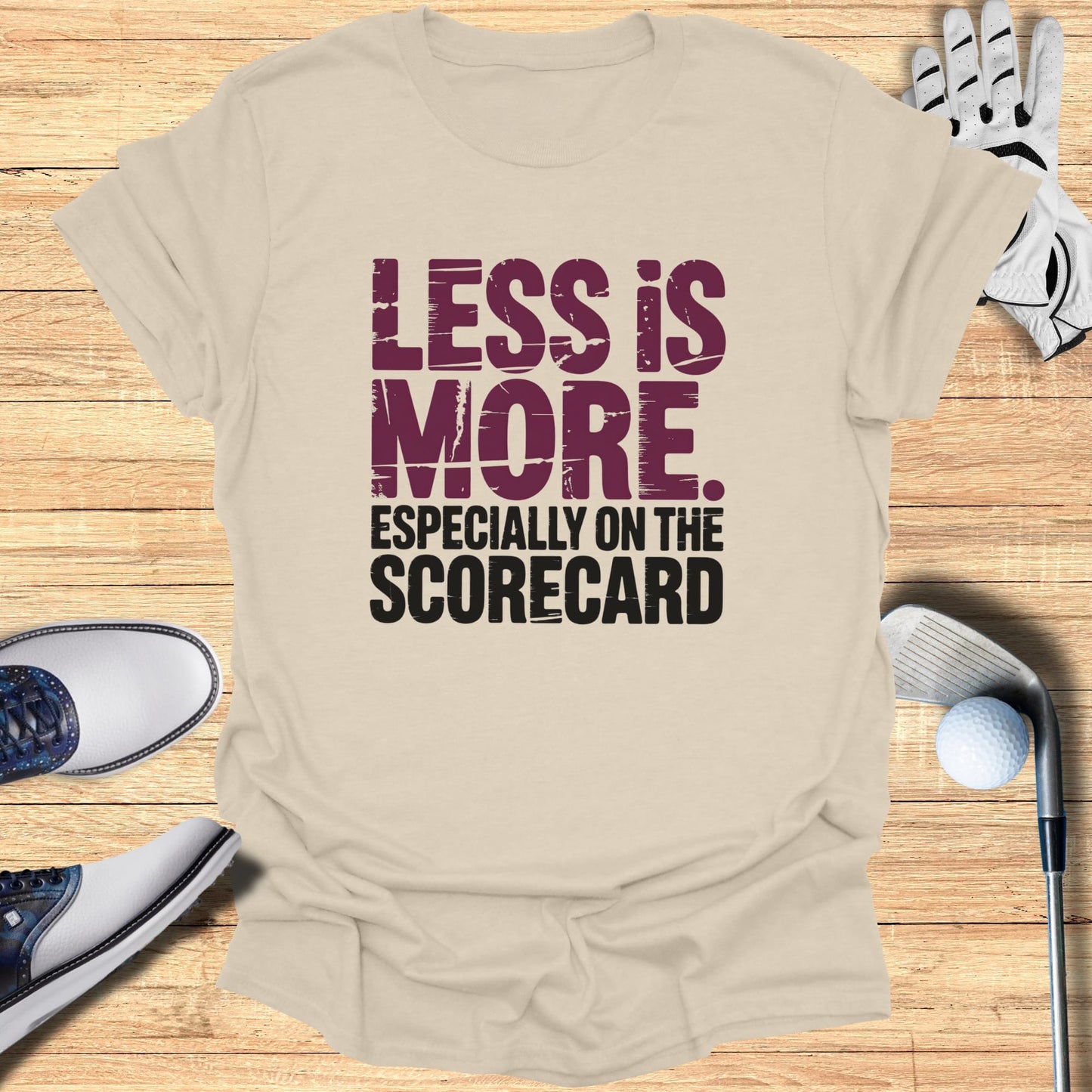 T-shirt with "LESS IS MORE. ESPECIALLY ON THE SCORECARD." text and golf items.