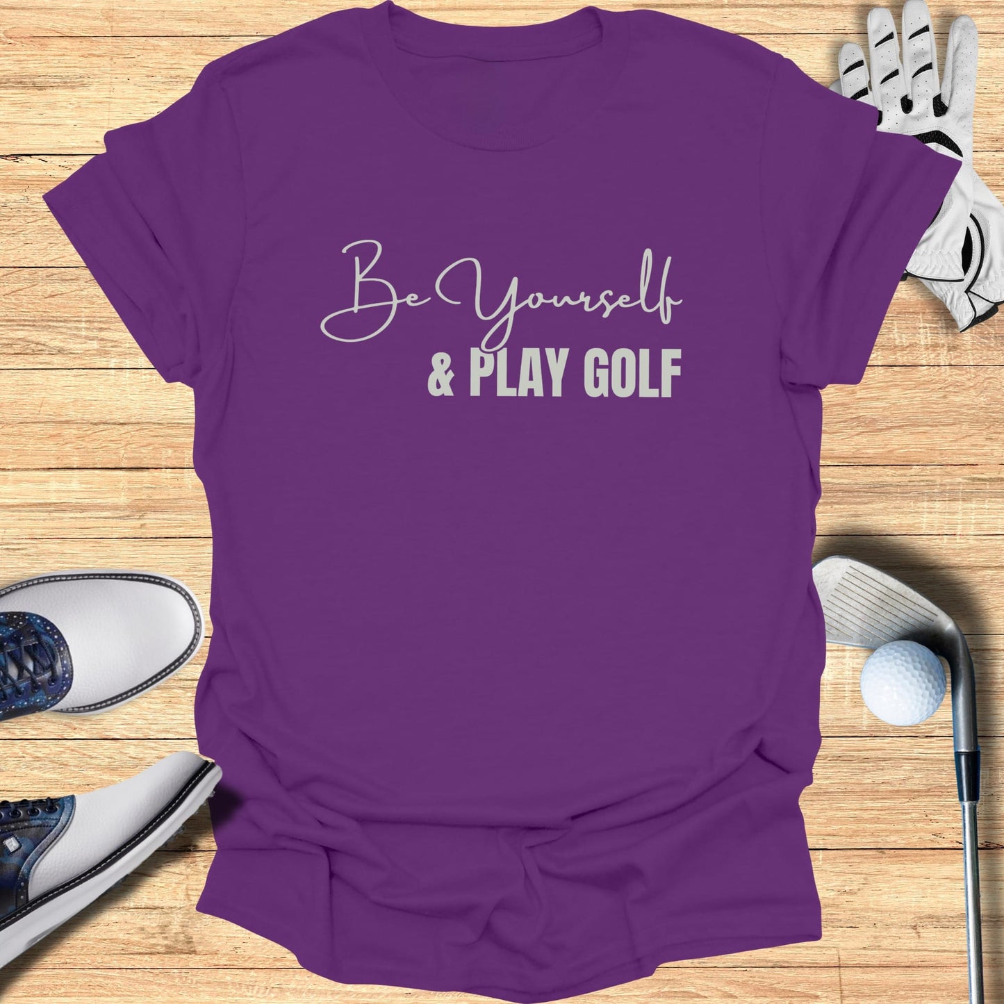Purple t-shirt with "Be Yourself & Play Golf" text, golf shoes, glove, and club.