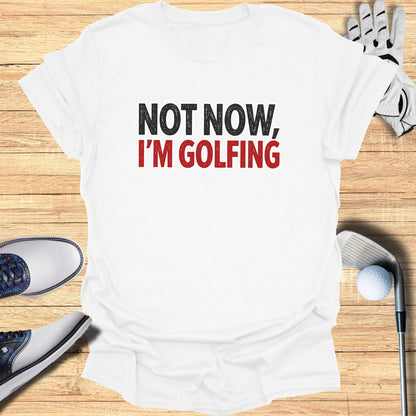 White t-shirt with black and red text "NOT NOW, I'M GOLFING".