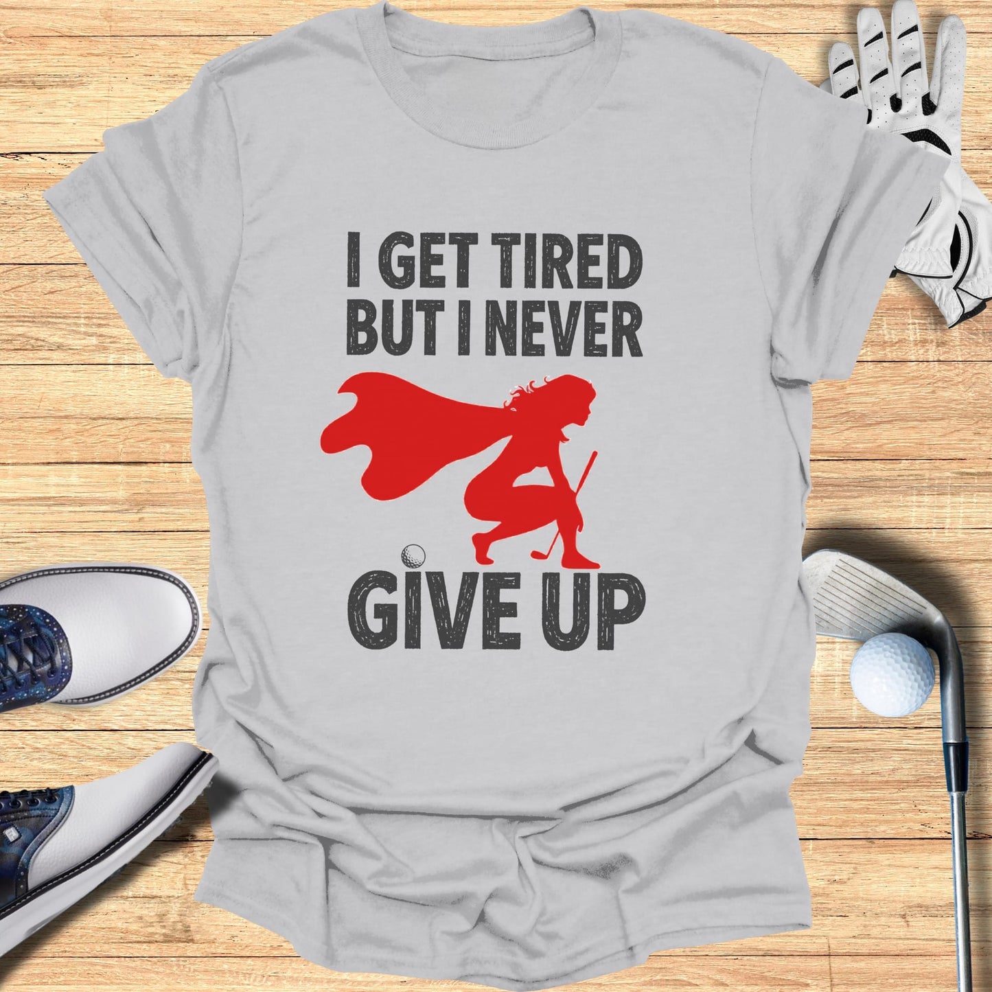 Grey t-shirt with graphic "I GET TIRED BUT I NEVER GIVE UP" and a female golfer.