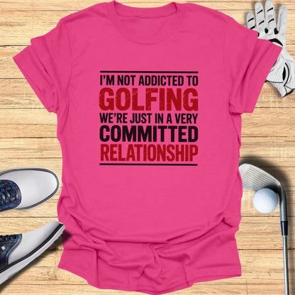 Pink t-shirt with black text stating "I'M NOT ADDICTED TO GOLFING WE'RE JUST IN A VERY COMMITTED RELATIONSHIP".