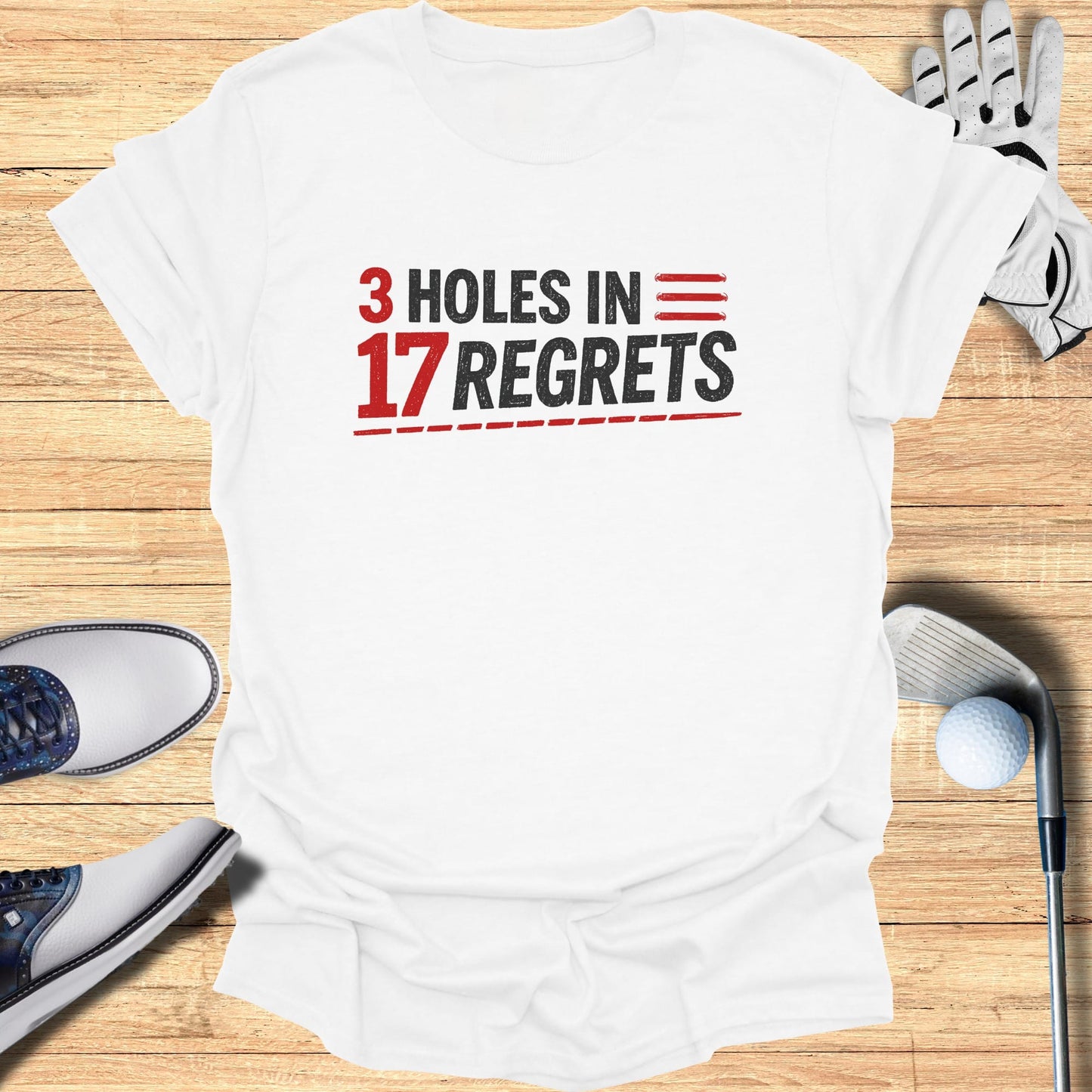 White t-shirt with red "3 HOLES IN 17 REGRETS" text and golf accessories.