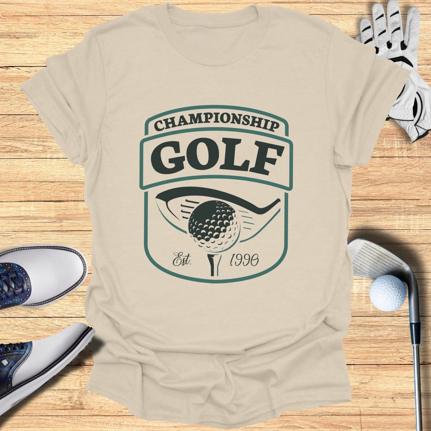Championship Golf Est. 1996 logo on a tan t-shirt with golf equipment.