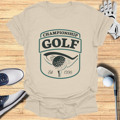 Championship Golf Est. 1996 logo on a tan t-shirt with golf equipment.