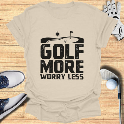 GOLF MORE WORRY LESS text graphic on a beige t-shirt with golf accessories.