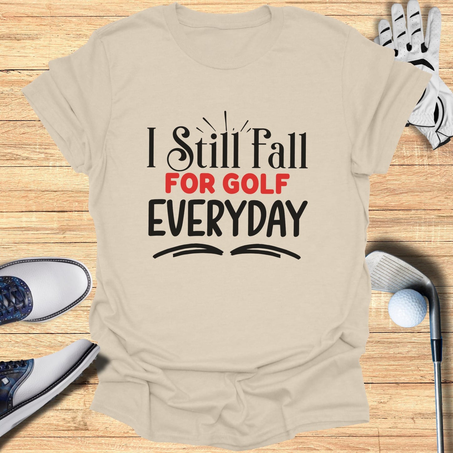 T-shirt with "I Still Fall FOR GOLF EVERYDAY" text and golf accessories.
