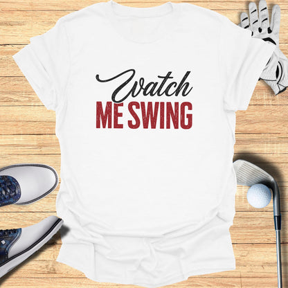 White t-shirt with "Watch ME SWING" text and golf accessories.