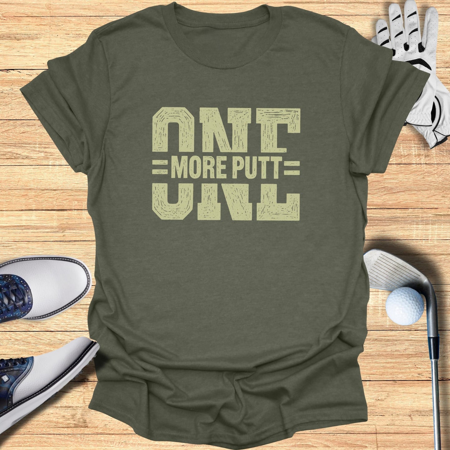 Olive green t-shirt with "ONE MORE PUTT" text, golf shoes, glove, and ball.