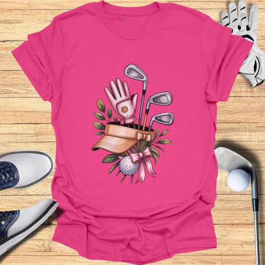 Pink t-shirt with golf clubs, glove, ball, and visor graphic.